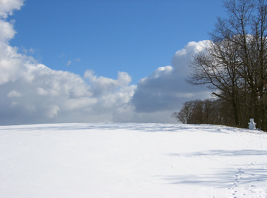 Schnee, Wolken, blauer Himmel und ein Schneemann